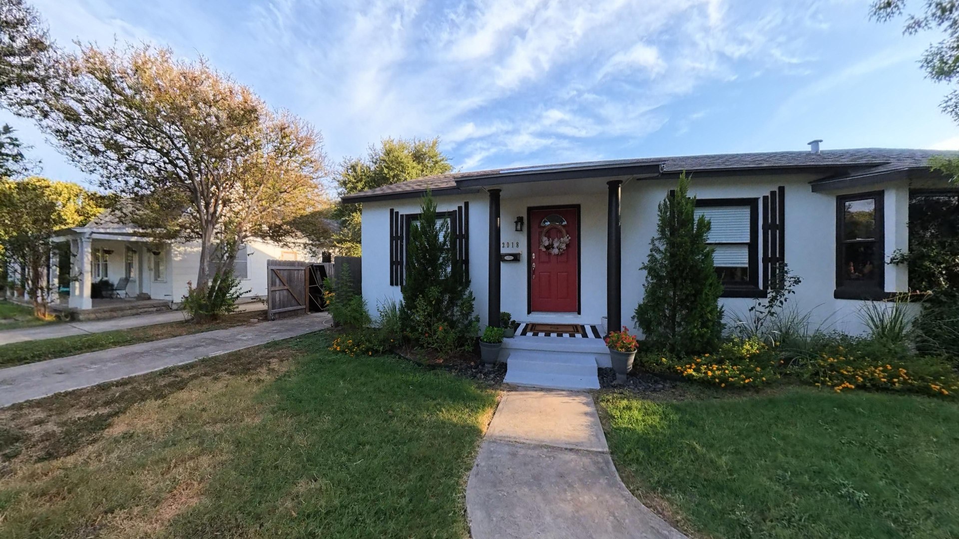 Front of 2018 W Mulberry with white exterior, dark shutters, red entry door and mature trees